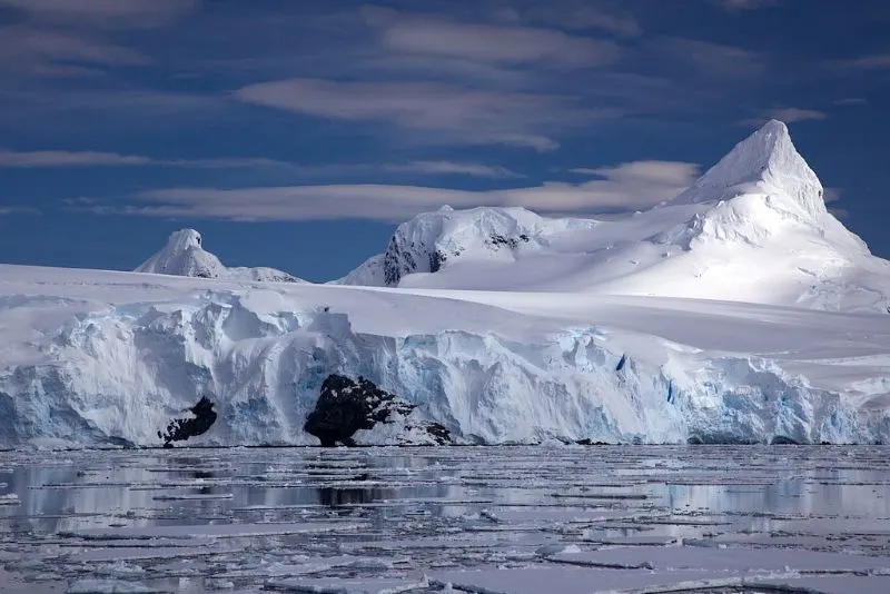 A tidewater glacier on the Antarctic coast with a sharply peaked mountain behind