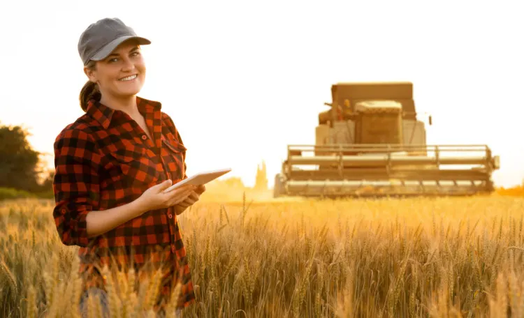 Woman farmer with digital tablet on a background of harvester
