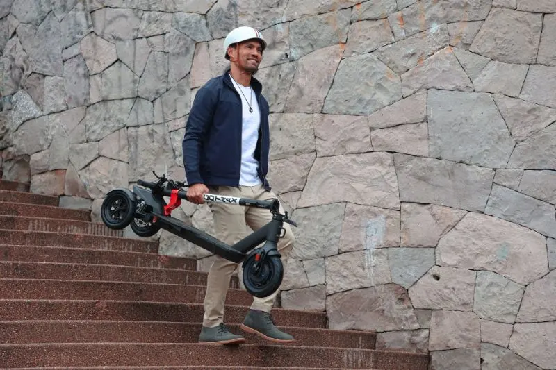15 Electric Scooters Pros and Cons to Know 9 Man holding a foldable electric scooter