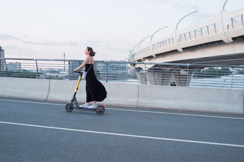 Woman in a dress using electric scooter