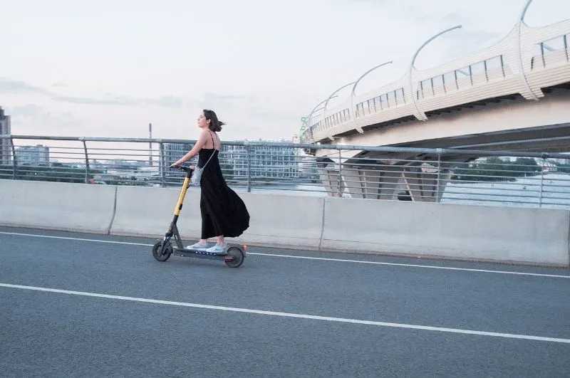 Woman in a dress using electric scooter