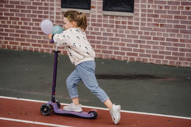 a small girl on a scooter