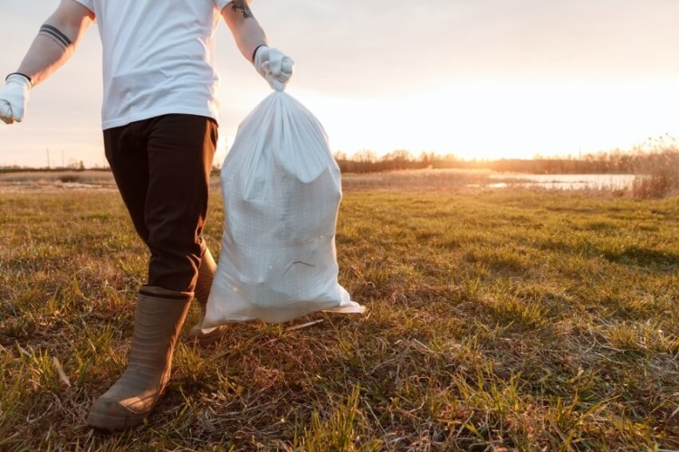 Man Holding a Trash Bag and Wearing Gloves