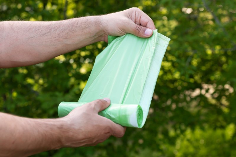 Holding  plastic garbage bio bag in roll outdoors