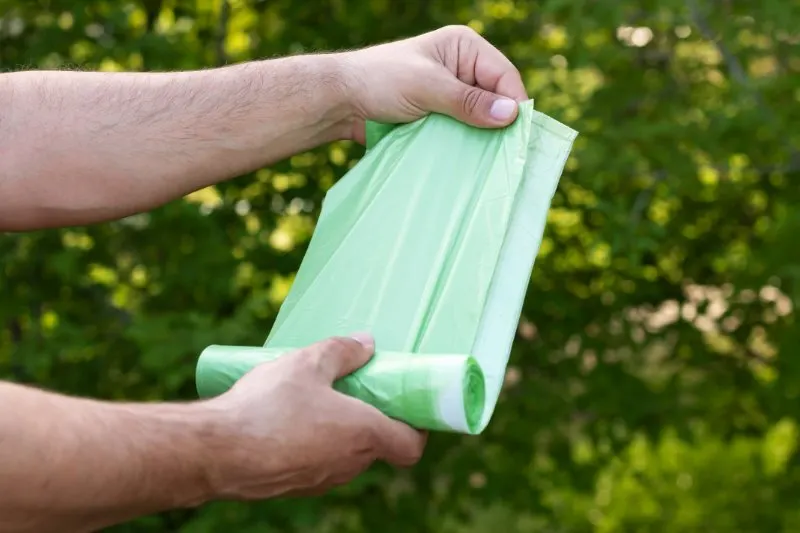 Biodegradable vs Compostable: What is the Difference? 6 Holding plastic garbage bio bag in roll outdoors