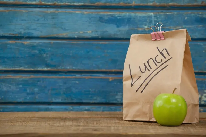 Brown Paper bag and apple placed on a table