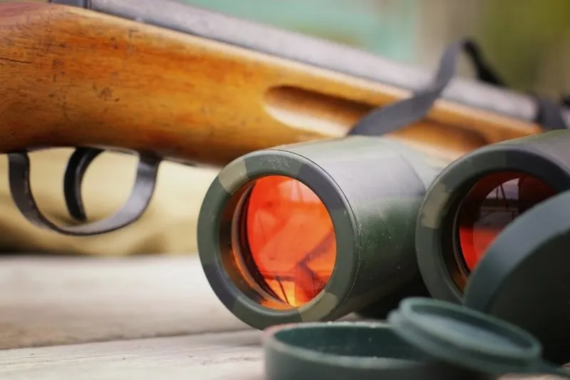 binoculars hunter shotgun placed on a table