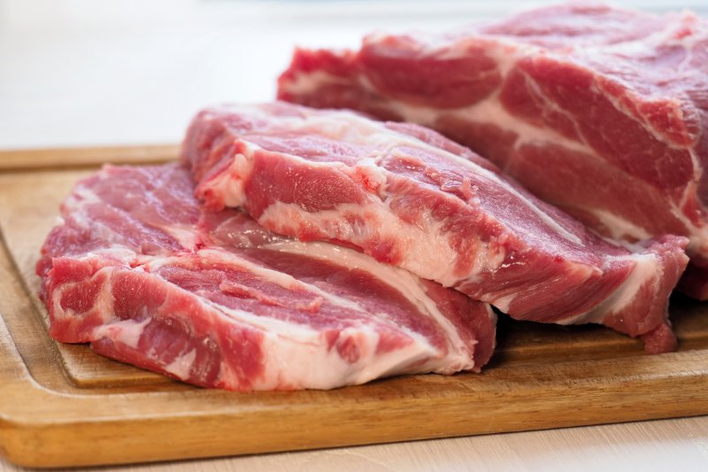 piece of beef and slices on wooden cutting board