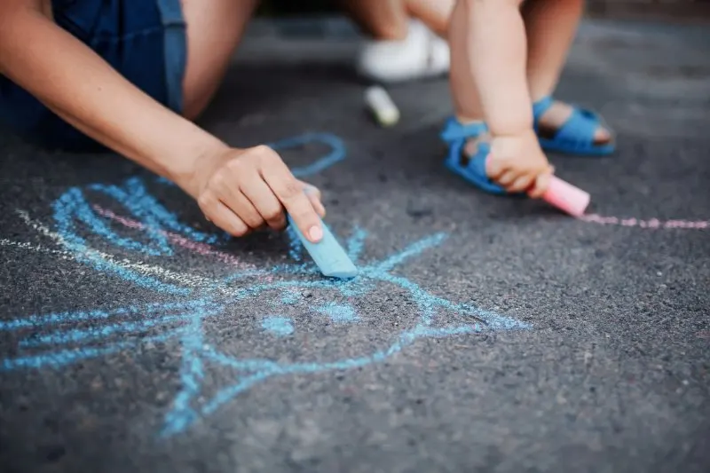 Close up of little girl drawing with chalks on the sidewalk