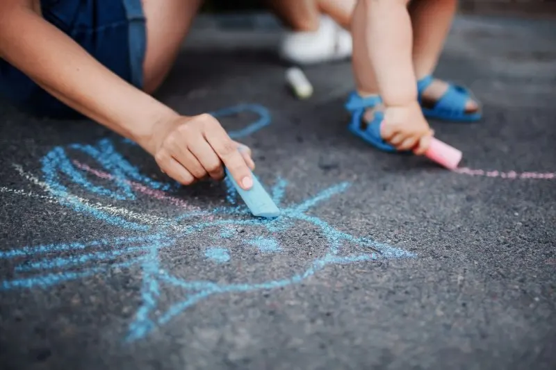 Is Sidewalk Chalk Bad for the Environment? 4 Close up of little girl drawing with chalks on the sidewalk
