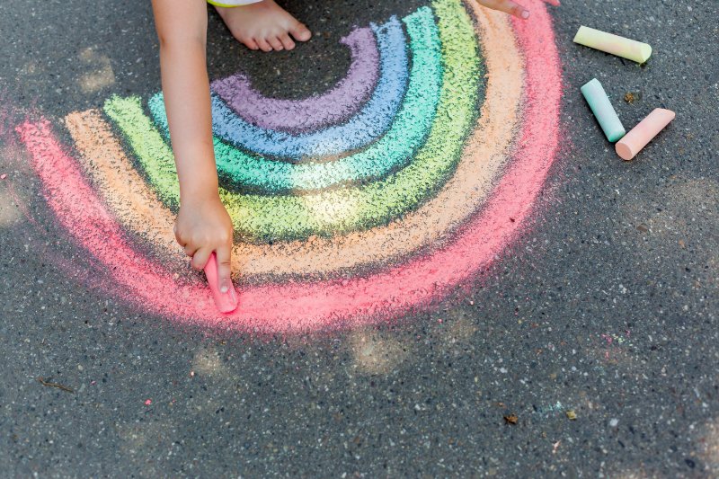 child's drawing  rainbow with colorful chalks on a street