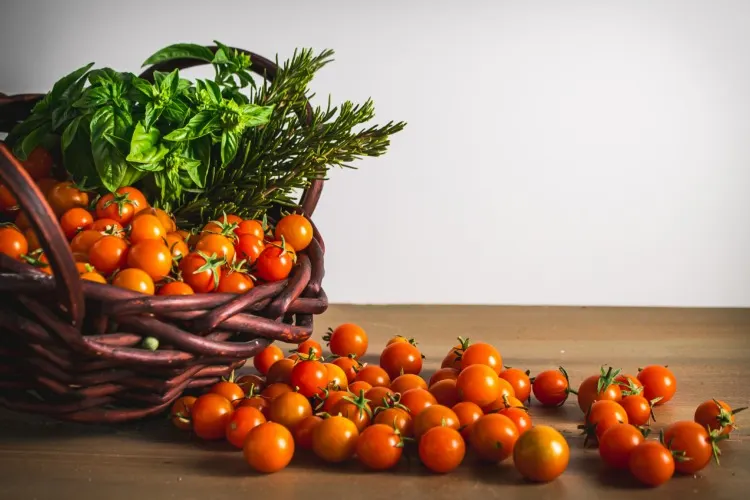 Sungold tomatoes and herbs spilling out of a basket