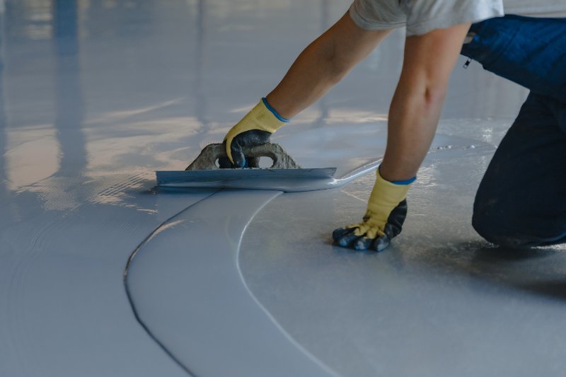 The worker applies gray epoxy resin to the new floor