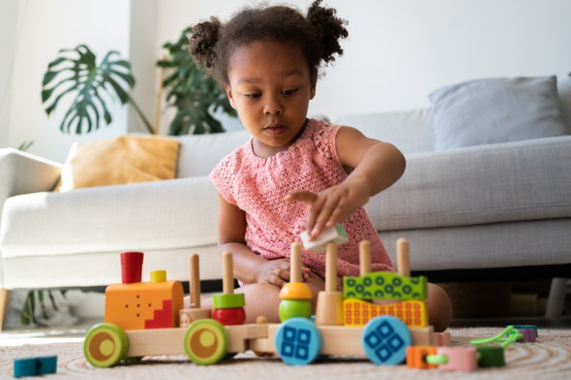 kid playing with colourful  wooden railway station at home.