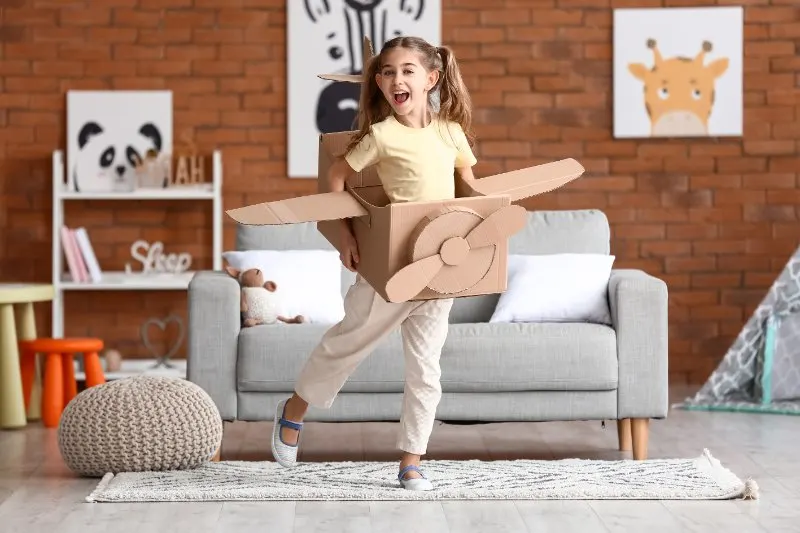 Little girl playing with cardboard airplane 
