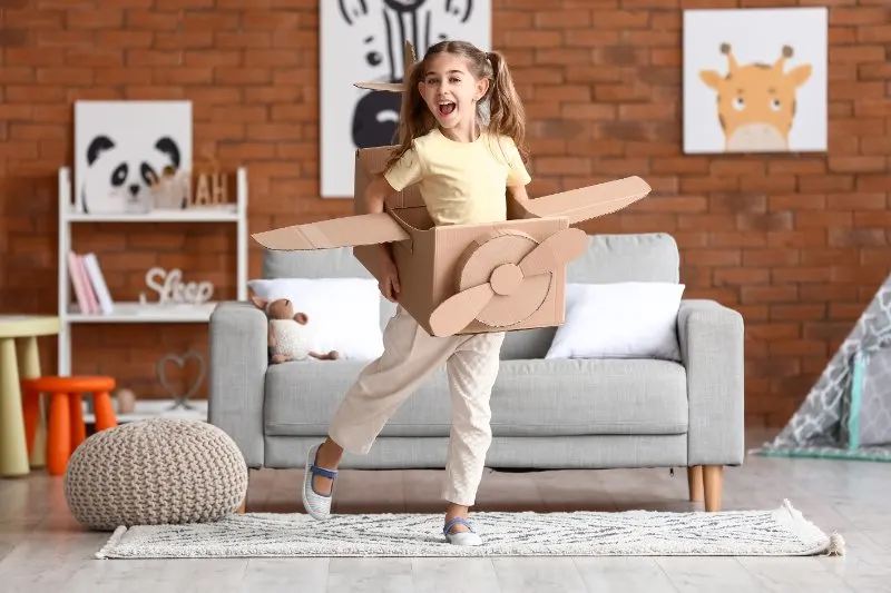 10 Best Sustainable, Eco-Friendly Toys for Kids 14 Little girl playing with cardboard airplane