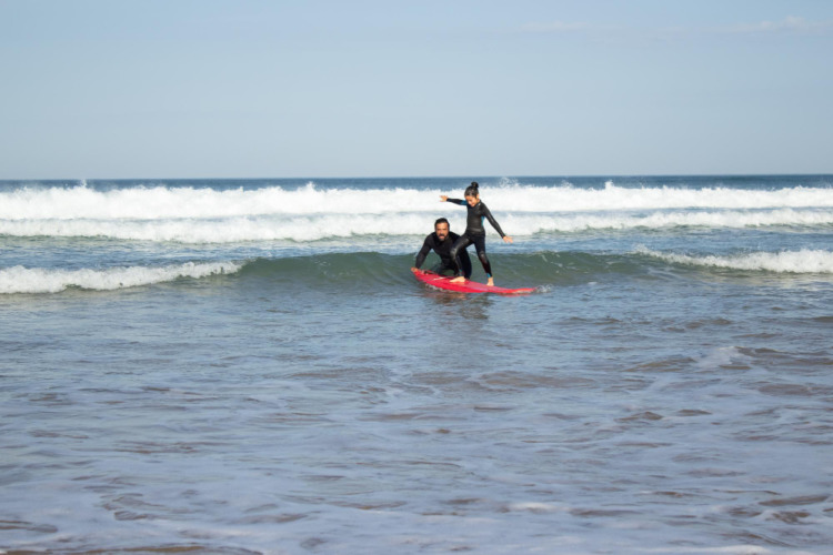 A surfer teaching a kid to surf