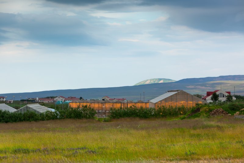 Geothermal Greenhouse at dusk, lights , blue sky,clouds, mountains, grass