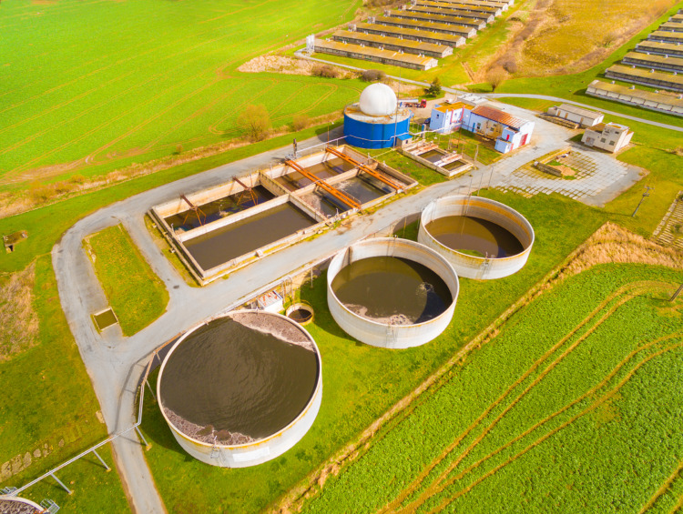 Aerial view to biogas plant from pig farm in green fields. Renewable energy from biomass.