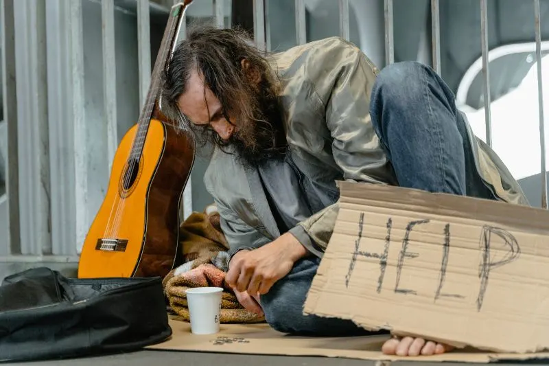 bearded man sitting on the ground asking for help