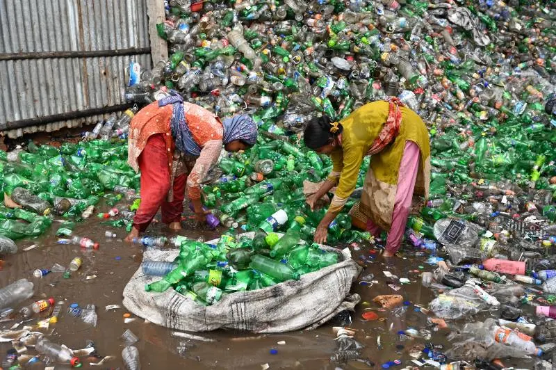 two women picking up plastic bottles