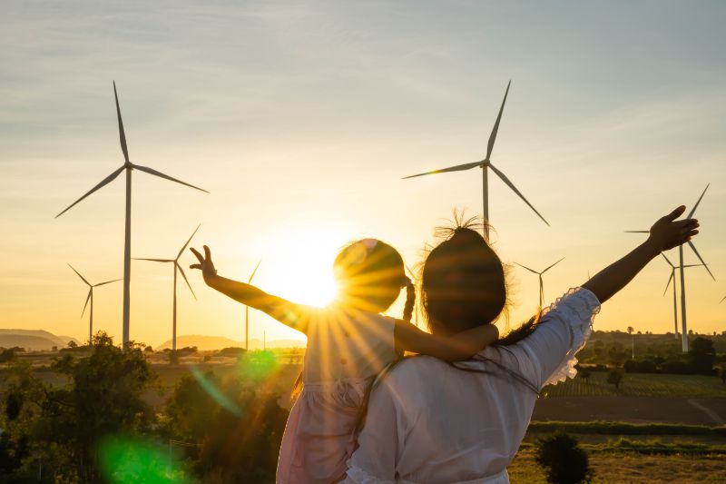 Mom and daughter happy living off-grid in front of wind turbines