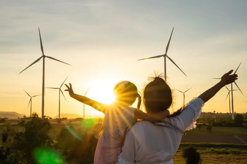 Mom and daughter happy living off-grid in front of wind turbines