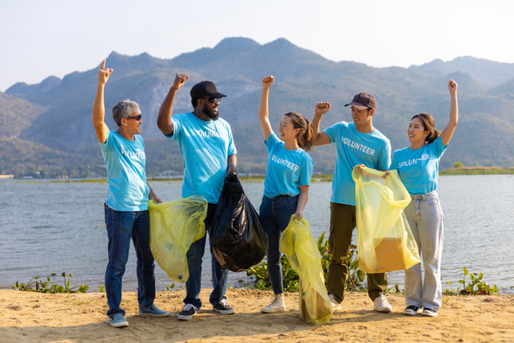 Team of young and diversity volunteer worker group enjoy charitable social work outdoor in cleaning up garbage and waste separation project at the river beach