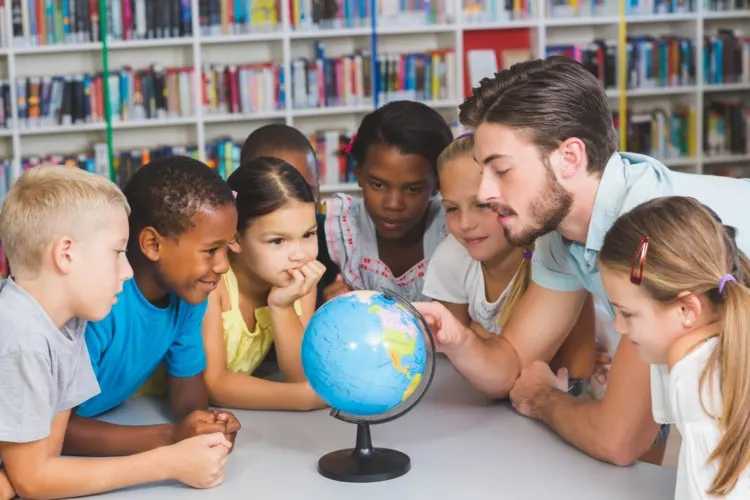 Pupils and teacher looking at globe in library