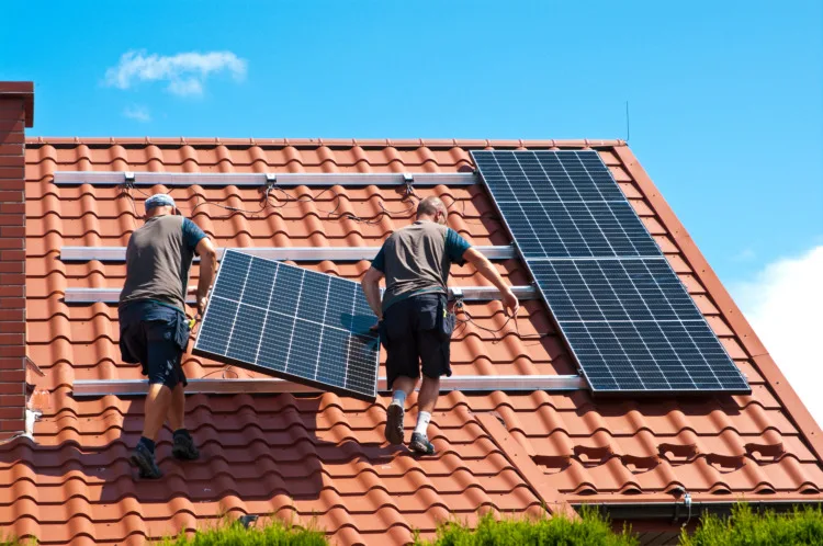 Two men installing new solar panels on the roof of a private house. Renewable energy concept and green energy abstract.