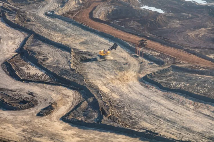 Aerial view of Canadian commercial excavator surface mining on site for Oilsands a giant dump truck loaded and heading to nearby refineries travel