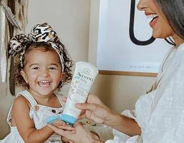 Baby and mom trying on aveeno product