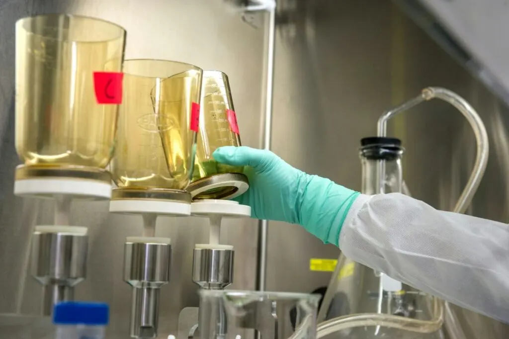 Chemist reaching for a chemical glass bottle
