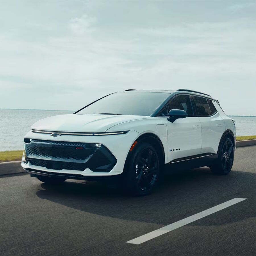 10 Most Eco-Friendly Cars for Different Lifestyles in 2026 18 White Chevrolet Equinox EV LT 1 FWD on a scenic road by the ocean, showcasing its sleek design and modern features.