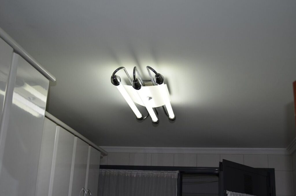 Do Energy-Efficient Light Bulbs Give Off Radiation? 7 Ceiling light fixture with four fluorescent bulbs illuminated, casting bright light in a room.