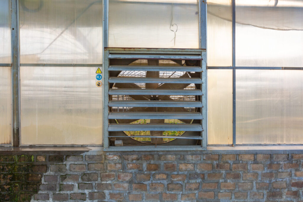 16 Best Lean-To Greenhouses for Small Yards & Side Walls 19 Large exhaust fan mounted in a greenhouse, designed for effective ventilation and air circulation.