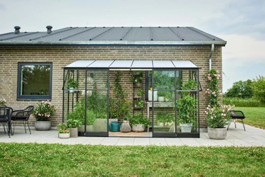 16 Best Lean-To Greenhouses for Small Yards & Side Walls 11 Compact lean-to greenhouse filled with potted plants on a patio, emphasizing a vibrant garden space.