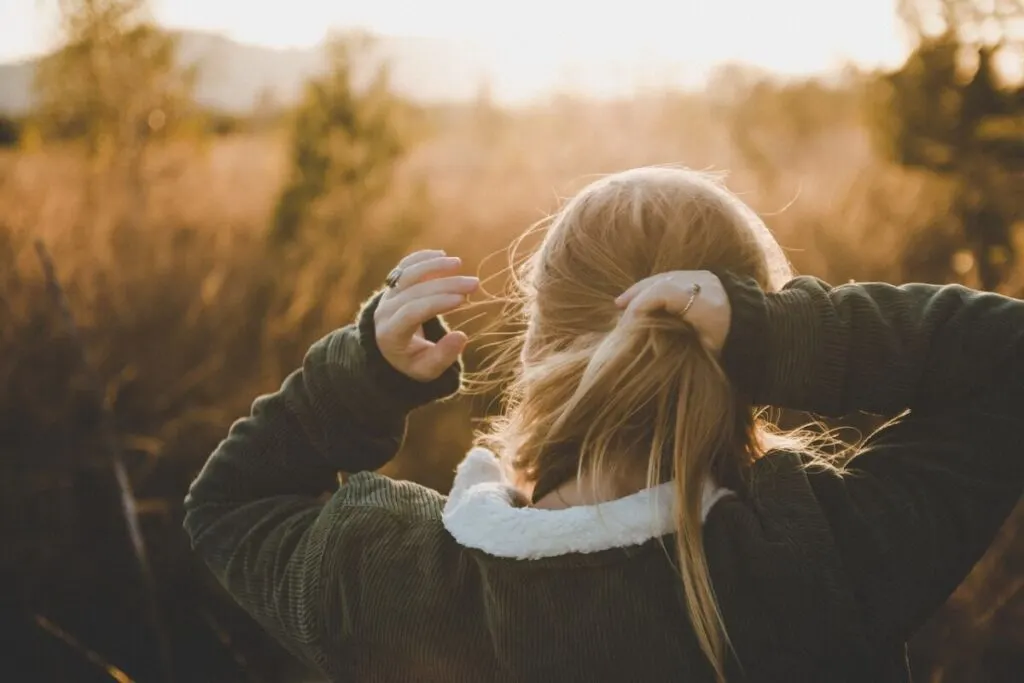Is Dry Shampoo Bad for the Environment? 3 Woman brushing and holding her hair outdoors