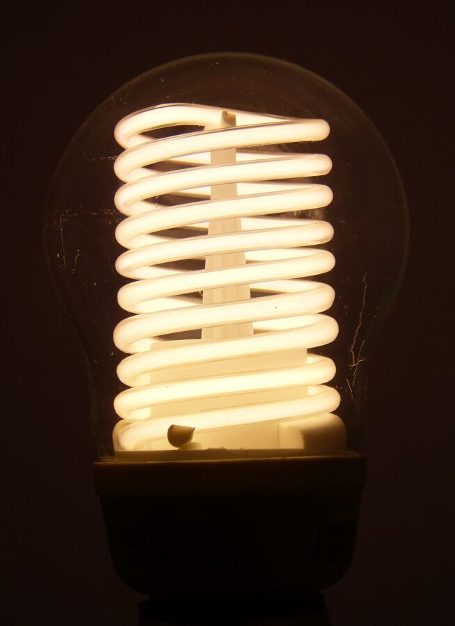 Do Energy-Efficient Light Bulbs Give Off Radiation? 9 CFL bulb glowing brightly, featuring a distinctive spiral light structure inside.
