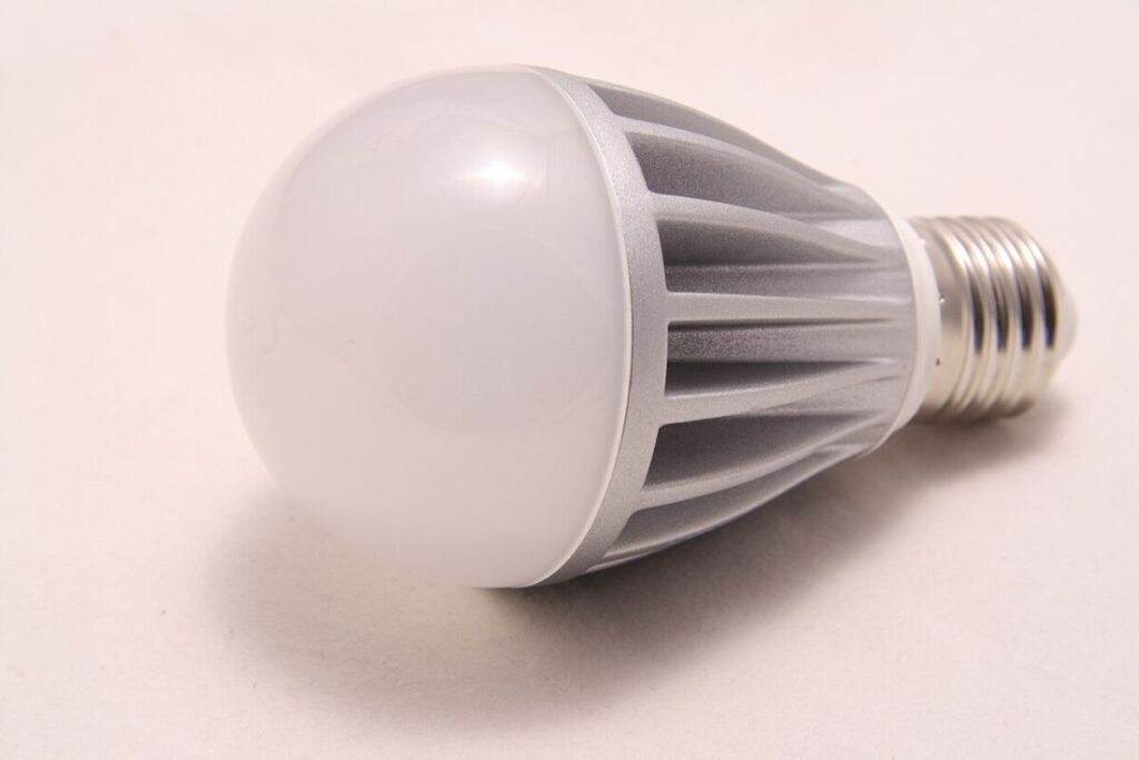 Do Energy-Efficient Light Bulbs Give Off Radiation? 6 Close-up of a white LED light bulb resting on a white surface, showcasing its smooth design and bright illumination.