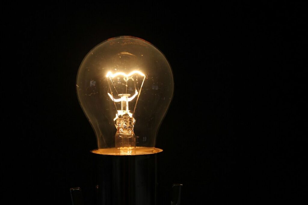 Do Energy-Efficient Light Bulbs Give Off Radiation? 13 Bright light bulb illuminated on a black background, highlighting its intricate filament and smooth glass surface.