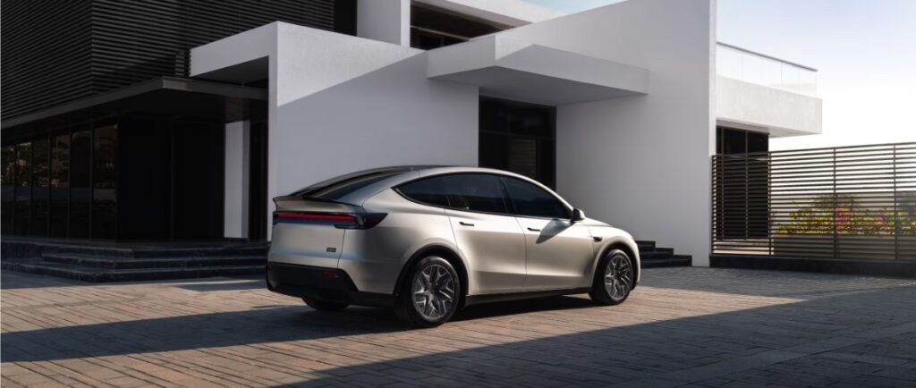 10 Most Eco-Friendly Cars for Different Lifestyles in 2026 7 Tesla Model Y Standard RWD parked in front of a contemporary house with large windows and a sleek design.