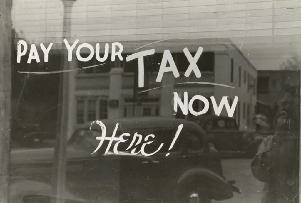 Carbon Inequality: How the Richest 1% Drive Climate Change 2 Vintage storefront window painted with the words Pay Your Tax Now Here