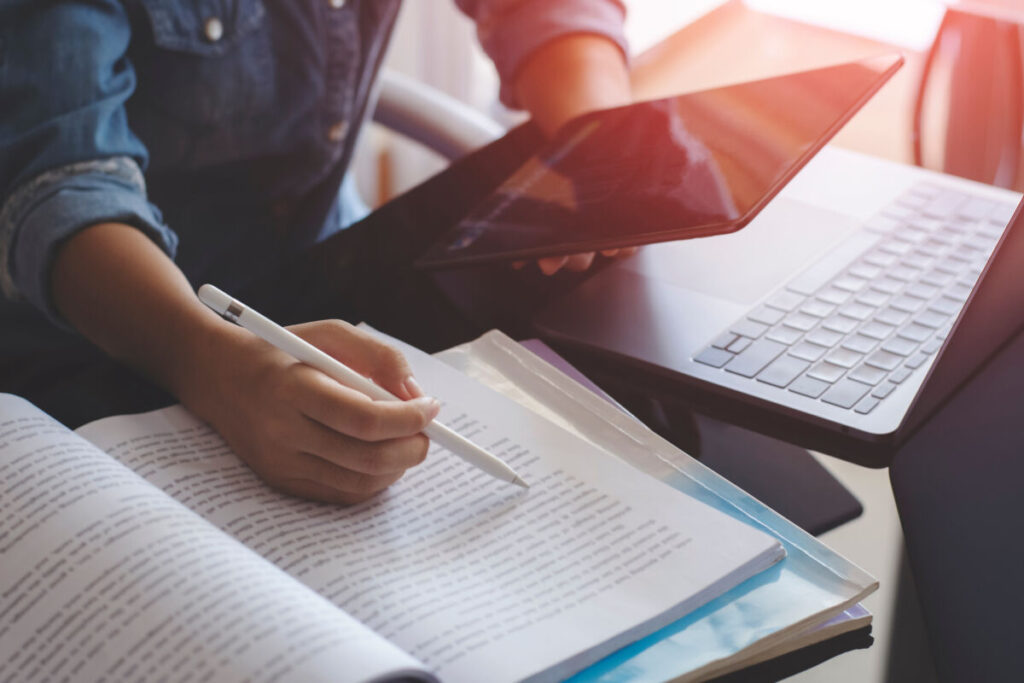 11 Best Books on Pollution: Air, Water, Plastic & Noise 3 Young woman multitasking with a tablet, laptop, and book at home, illustrating online education and study habits.