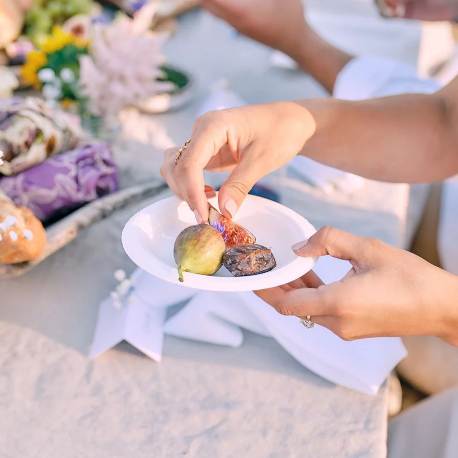 11 Best Compostable Plates for Parties and Everyday Meals 17 Woman holds a 6-inch compostable dessert plate filled with food at a wedding reception, smiling in a festive atmosphere.
