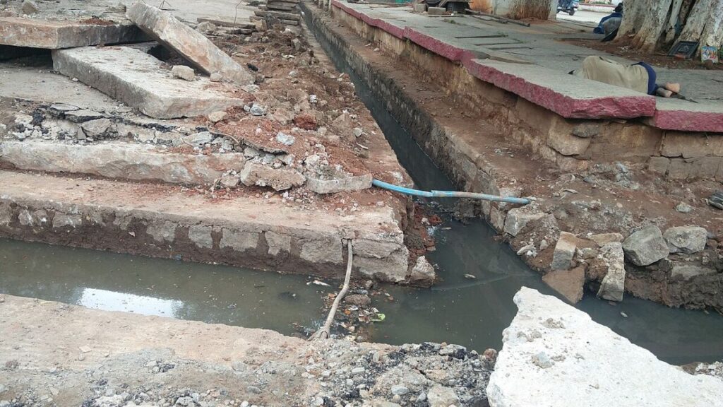 4 Types of Water Pollution: Sources, Effects, and Examples 10 Installation of a sewage water pipe in an urban street, with workers and machinery present in the scene.