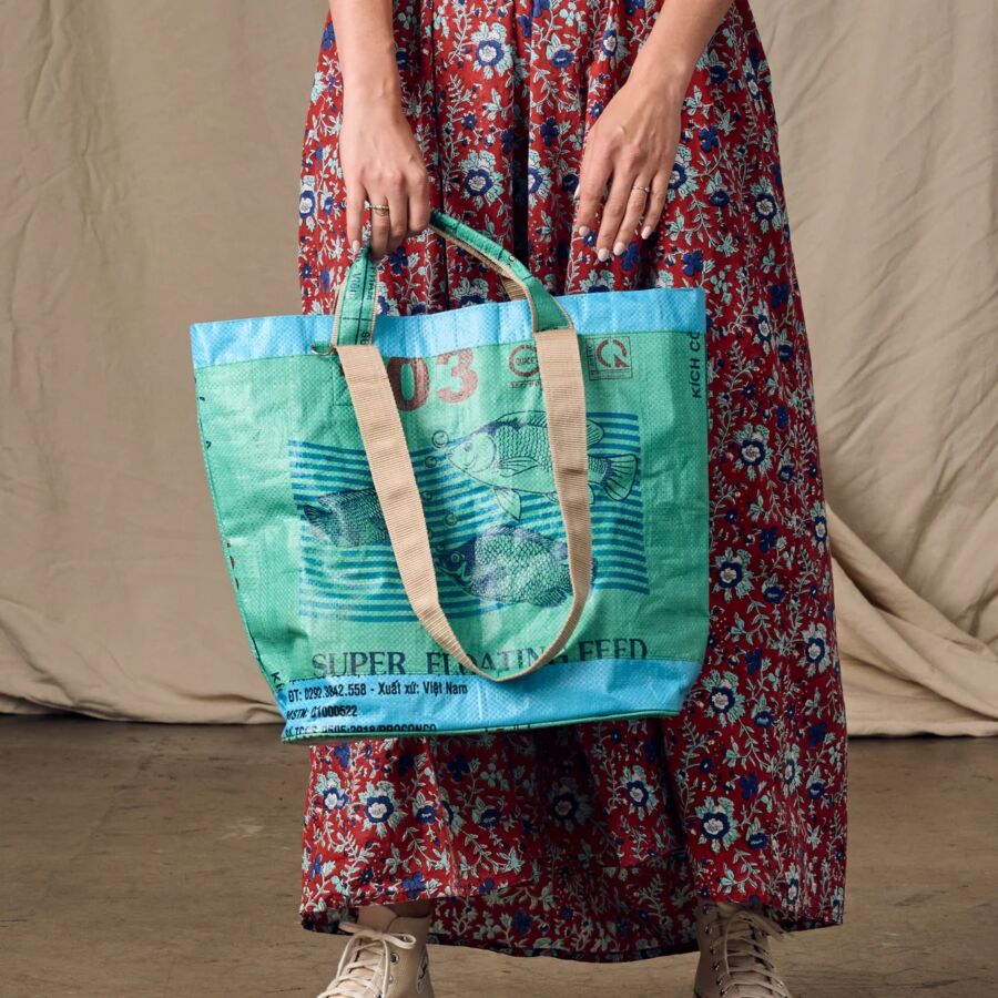 10 Best Fair Trade Handbags for 2026 12 Woman displays a large green shopping bag from Ten Thousand Villages, emphasizing its size and eco-friendly appeal.