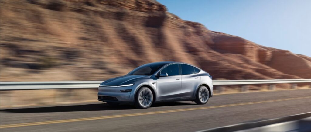 10 Most Eco-Friendly Cars for Different Lifestyles in 2026 1 Tesla Model Y Standard RWD, an electric SUV, driving on a scenic road surrounded by greenery.