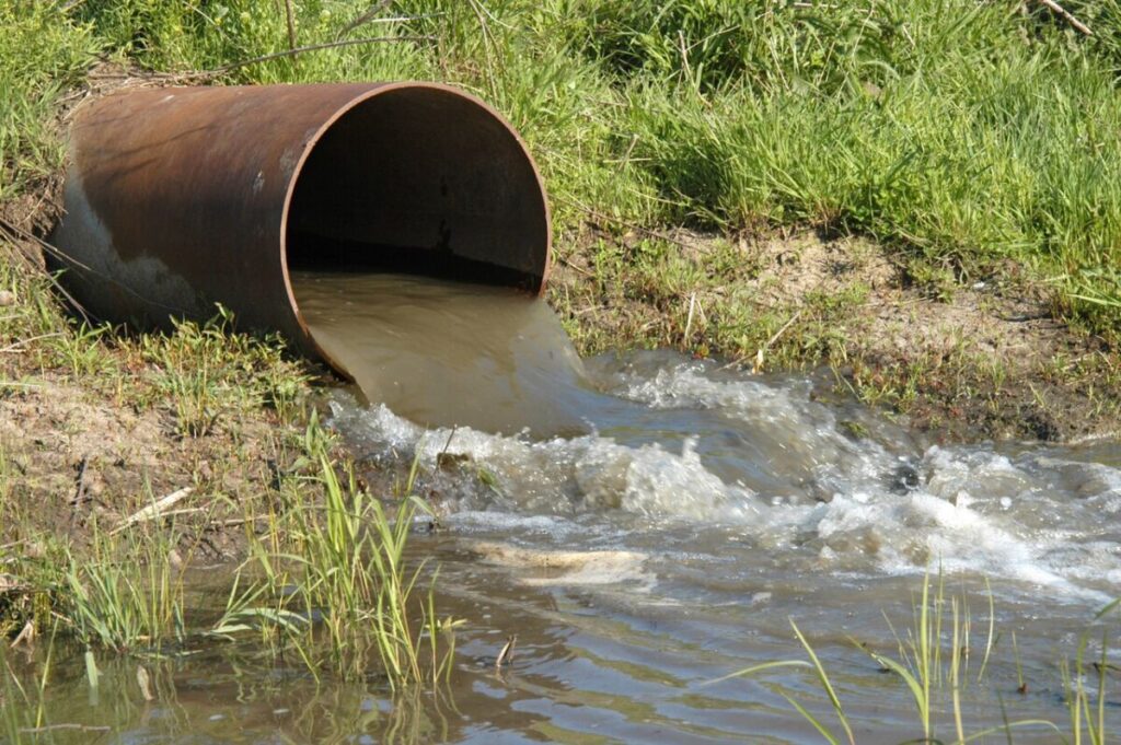 4 Types of Water Pollution: Sources, Effects, and Examples 9 Leaking pipe discharges water into a stream, highlighting issues of water waste and environmental impact.